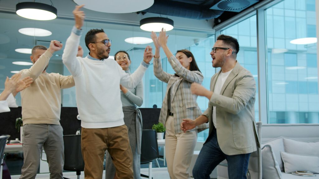 Team feiert im Büro ausgelassen einen gemeinsamen Erfolg